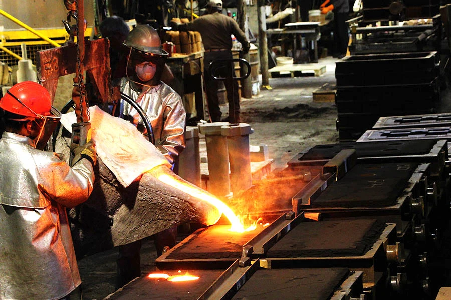 Foundry workers pouring molten metal